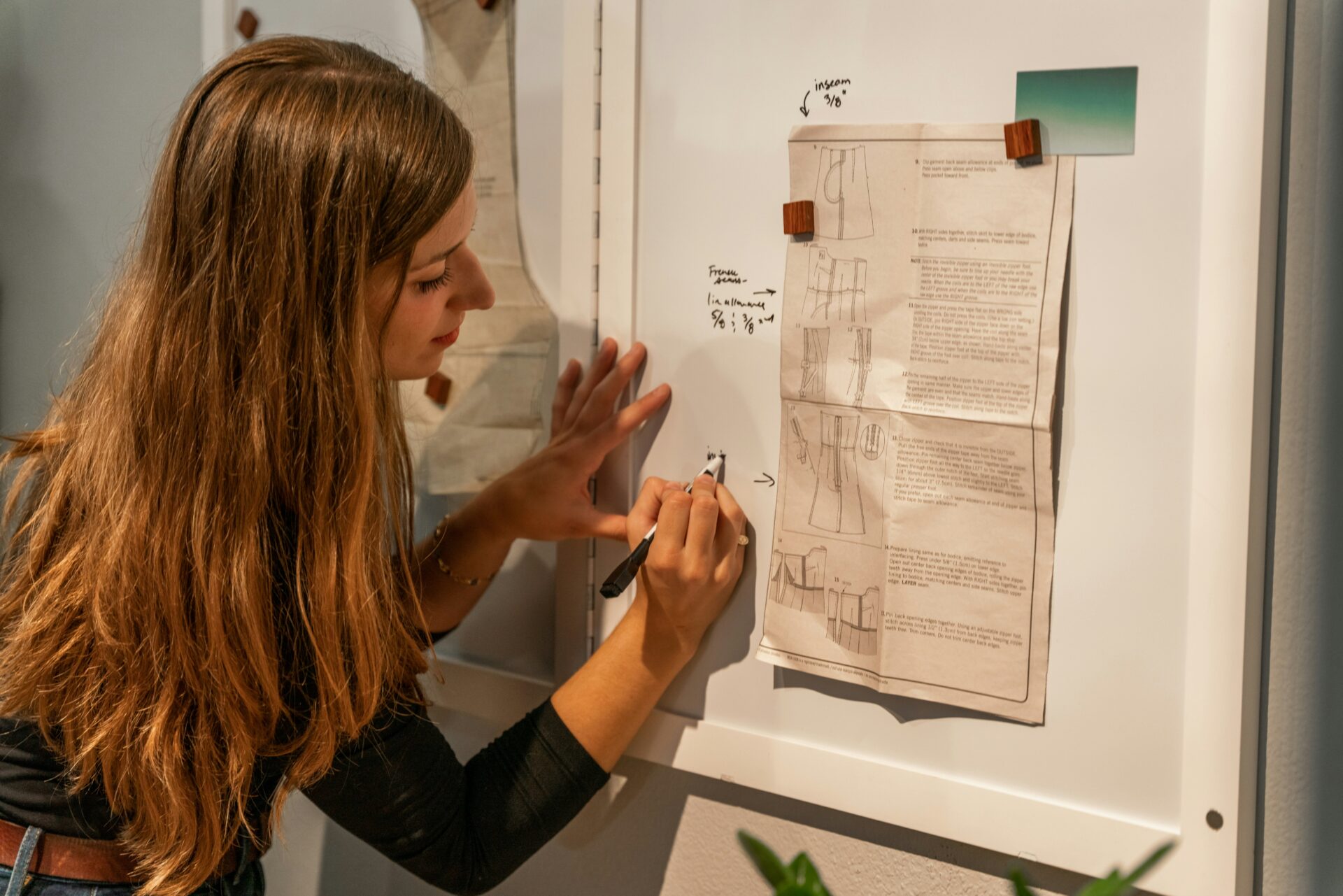 Mulher jovem escrevendo planejamento estratégico em quadro branco com anotações de comunicação digital.