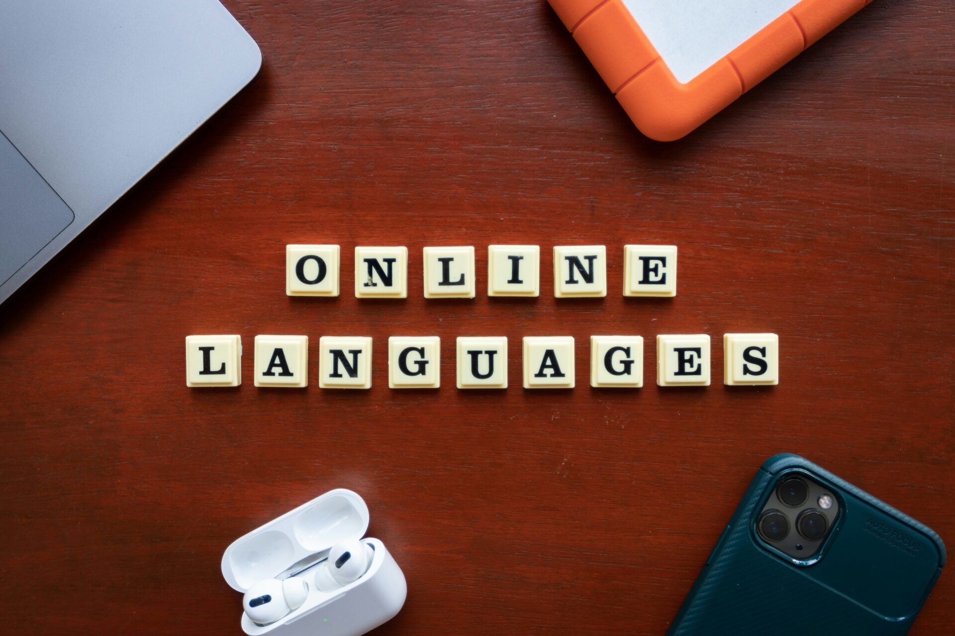 Peças de jogo formando a frase Online Languages sobre mesa de madeira representando o aprendizado de linguagem profissional.