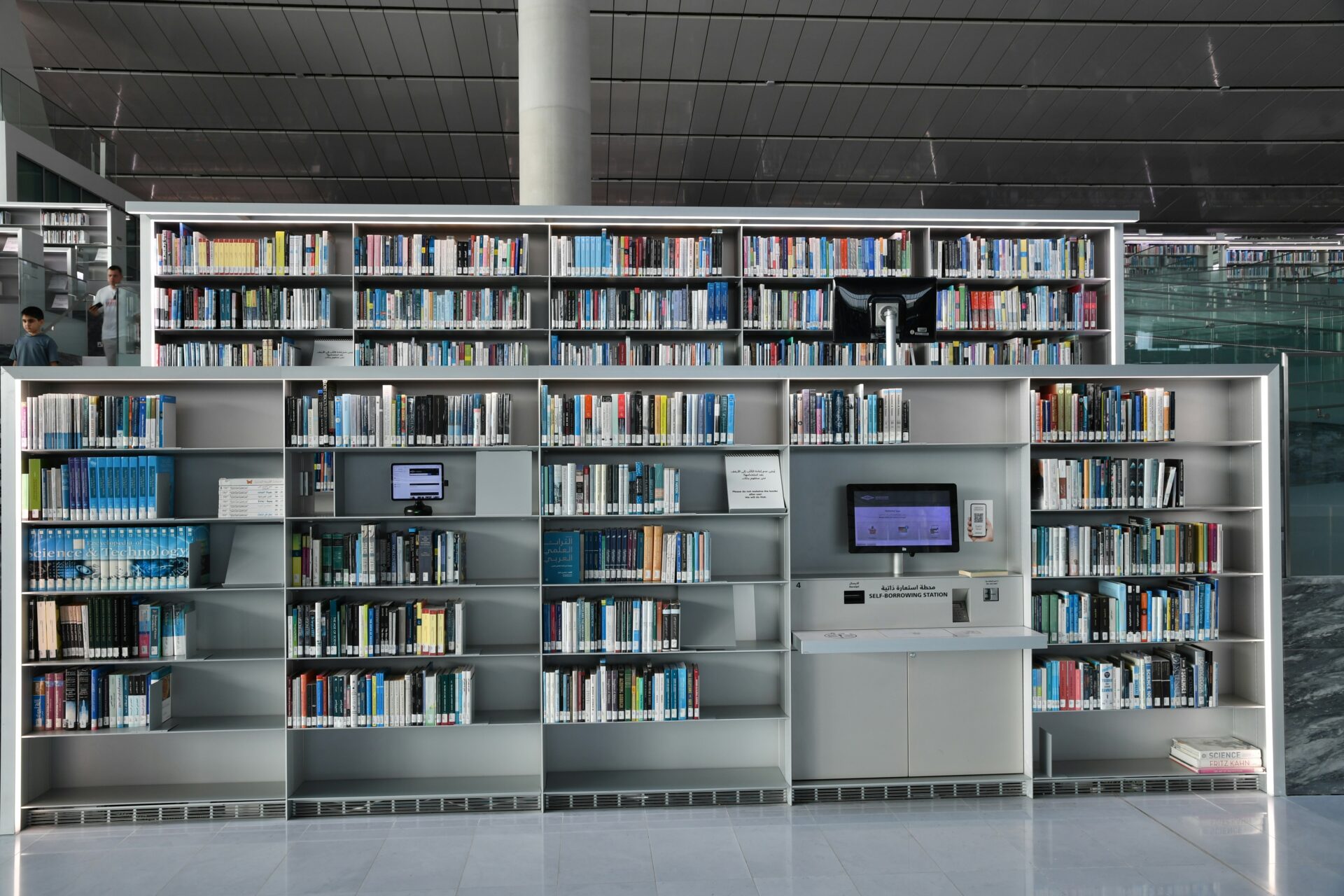 Prateleiras de biblioteca moderna com monitores integrados simbolizando a curadoria humana e tecnologia na escrita de e-mails.